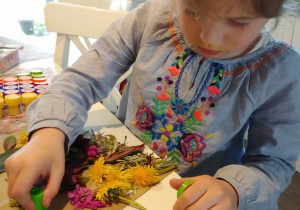 dziewczynka stempluje swoje imię na pracy z naturalnych okazów liści i kwiatów